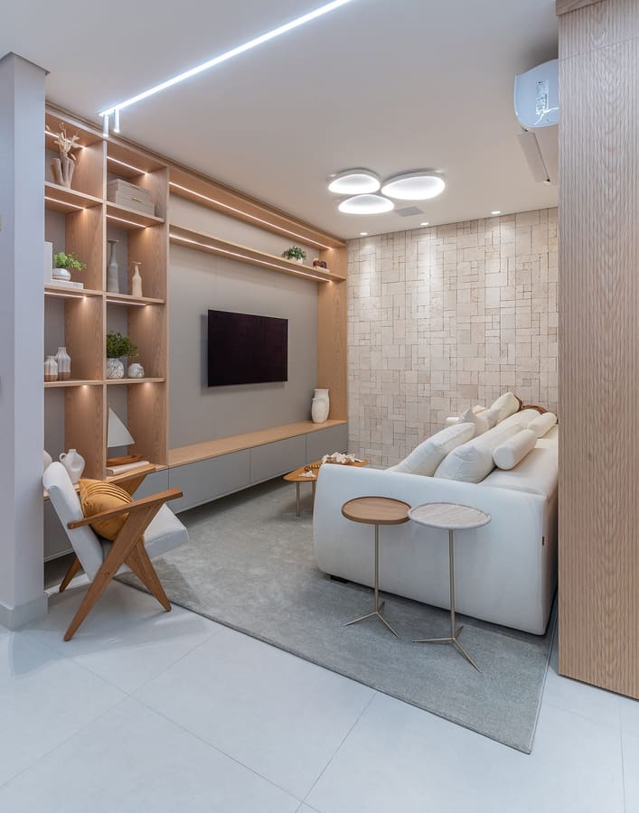Sala de estar com estante iluminada em madeira e painel de TV