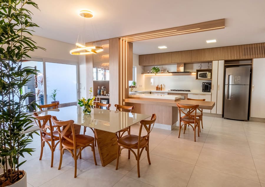 Cozinha integrada à sala de jantar, com ilha e pórtico em madeira iluminado