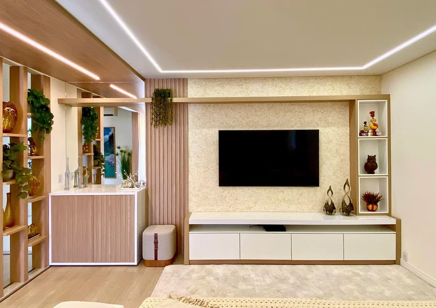 Sala de estar com painel de TV, rack claro e estante com plantas