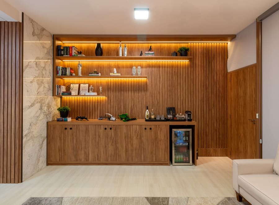 Painel em madeira com prateleiras iluminadas e frigobar embutido