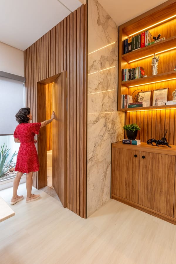 Porta pivotante ripada ao lado de estante iluminada com livros